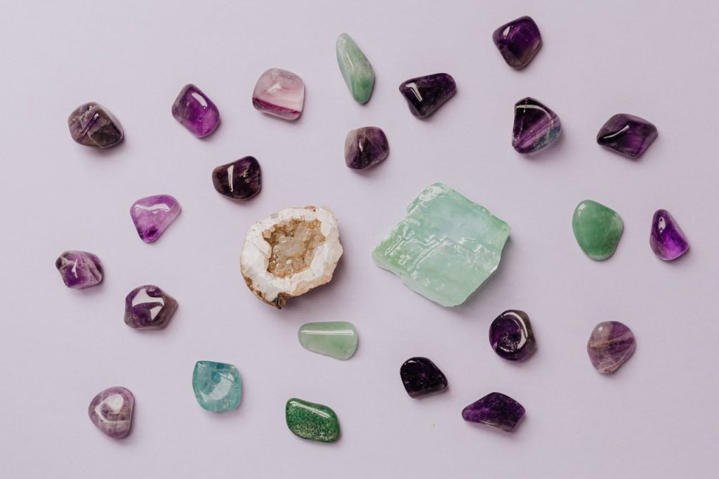 Flat lay of assorted polished gemstones including amethyst and jade on a light background.