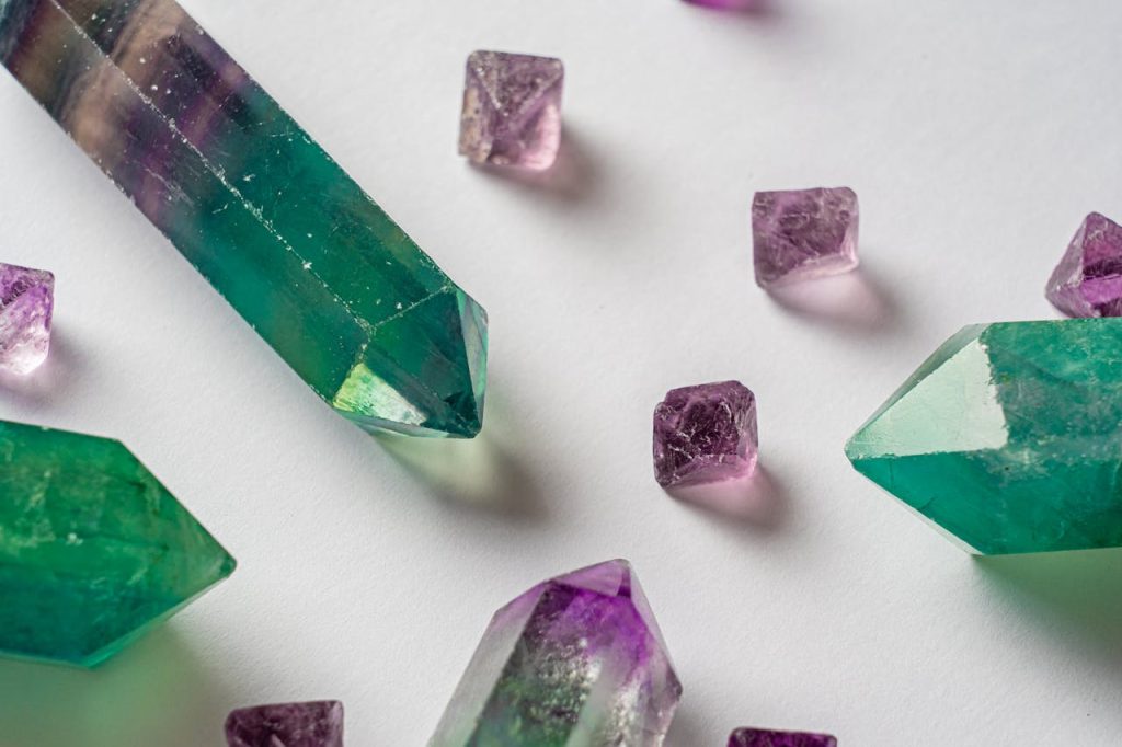 Discover intricately detailed green fluorite and purple amethyst crystals against a white backdrop.